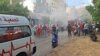 Smoke rises from a mobile shop as civil defence members gather in Sidon