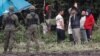 POLAND -- Polish border guard officers stand guard next to a group of migrants stranded on the border between Belarus and Poland near the village of Usnarz Gorny, September 1, 2021